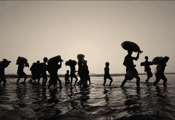 Silhouette of a group of people walking across a watery landscape